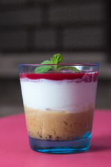 Tasty cheesecake in a glass cup on pink background