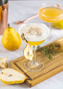 Pear Elderflower Cocktail. Champagne coupe glass filled with pear puree cocktail or mocktails surrounded by ingredients and bar tools