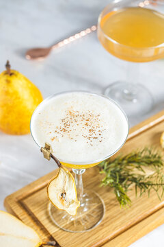 Pear Elderflower Cocktail. Champagne coupe glass filled with pear puree cocktail or mocktails surrounded by ingredients and bar tools