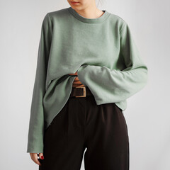 Young woman wearing pastel green crop sweater and black trousers isolated on white background.