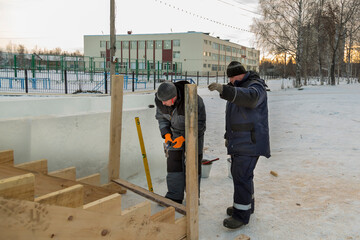 Workers on the installation of the frame of a wooden slide