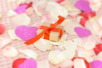 Rose petals on a white background. A gift on Vlentin's day, on his birthday. A gift in craft paper.