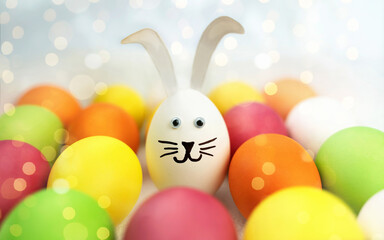 Fototapeta na wymiar Funny bunny among colorful easter eggs. Background with bokeh