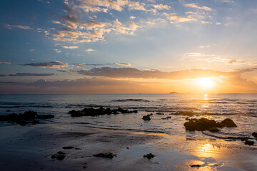 Fototapeta na wymiar sunset landscape on the beach rocks in foreground