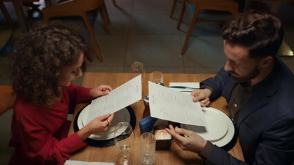 Lovers looking restaurant menu on evening dinner date. Romantic cafe concept.