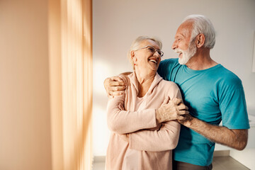 A happy senior couple hugging and laughing at nursing home.