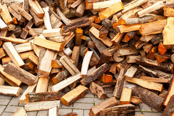 Background in the form of firewood chopped for heating the house, stacked randomly. Closeup.