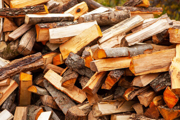 Background in the form of firewood chopped for heating the house, stacked randomly. Closeup.