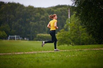 Taking in a park run. Shot of a woman jogging along a foothpath in a park.