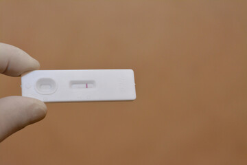 A closeup of medical personnel holds a negative pregnancy HCG test on beige background, Human...