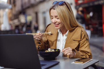 Woman eating food using chopsticks in street cafe