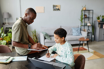 Portrait of African American father helping teenage girl studying at home in green interior, copy space