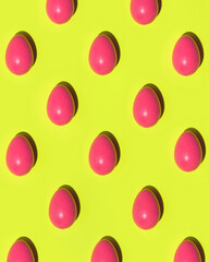 Easter pattern made of pink eggs on yellow background. Creative holiday concept.