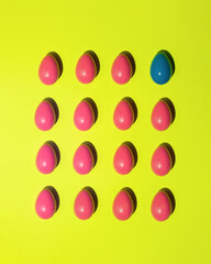 Easter pattern made of pink and blue eggs on yellow background. Creative holiday concept. Geometrical individuality, leadership or think different flat lay composition.