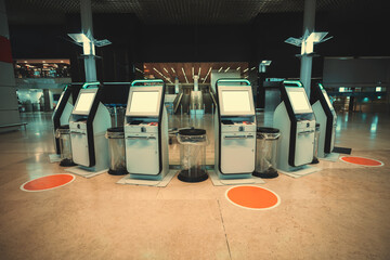 A curved set of self-serve flight check-in electronic kiosks in an airport with mockups of LCD...