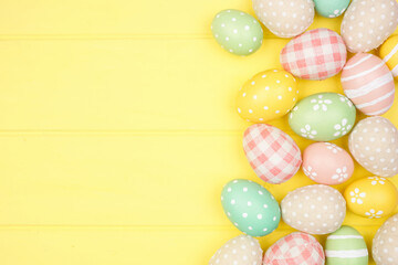 Fototapeta na wymiar Easter side border with modern farmhouse cloth and pastel eggs over a yellow wood banner background. Above view with copy space.