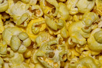 Yellow cheese flavored popcorn kernels up close with details and textures from directly above, selective focus.