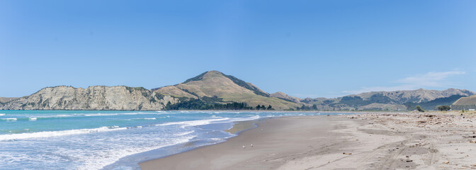 Panorama view of Tolaga Bay with surrounding hills under blue sky