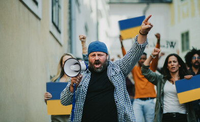 Crowd of activists protesting against Russian military invasion in Ukraine walking in street.