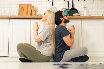 calm caucasian couple sitting on lotus pose on the floor at home and meditating during their self-care routine. High quality photo