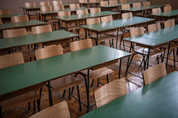 Empty old faculty or college School classroom with row of chairs and green desk tables. Natural light.