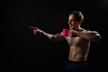 Man on black background keeps dumbbells pumped up in fitness bodybuilding chest sport, body muscular man hand, shirtless Attractive power, gym fit In the athlete's pink cup he smiles