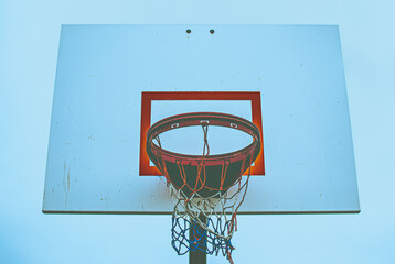 Old school basketball hoop at the park with a blue abstract vibe to the photography. An American patriotic net color of red, white, and blue.