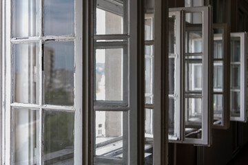 Row of old vintage white open windows in school classroom. Natural lighting trough the window. Closeup window frame.
