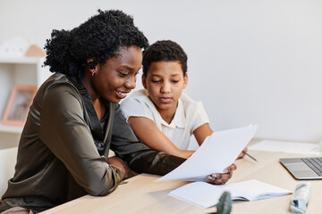 Portrait of smiling female tutor working with teenage girl studying at home, copy space