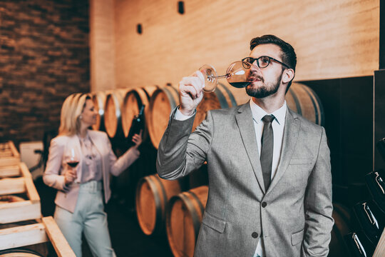 Good looking experienced sommelier tasting red wine in old-fashioned winery.