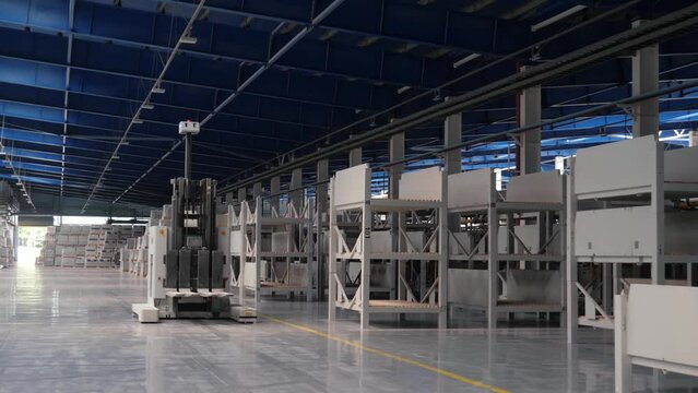 Modern production, automatic robot loader moves among the racks, logistics warehouse in the production of a tile factory