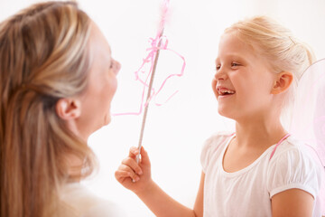 Ill make your wish come true. A smiling girl dressed up as a fairy and holding a wand standing infront of her mother.