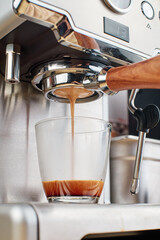 Making coffee, coffee extraction process using espresso machine, espresso machine pouring coffee into cup. vertical