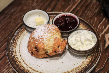 Scones with Strawberry Jam and Clotted Cream on wooden table black background. Delicious freshly baked homemade