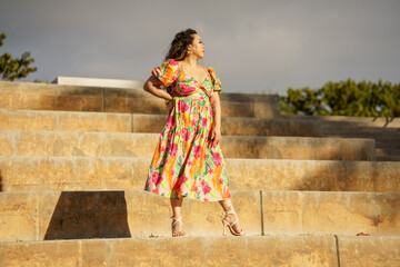 She is a confident woman posing in a floral dress