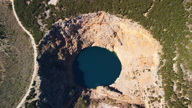 Flying over the Red Lake containing a karst lake close to Imotski, Croatia. The largest collapse doline in Europe with high cliffs and great depths. Beautiful scenic landscape view 4k UHD