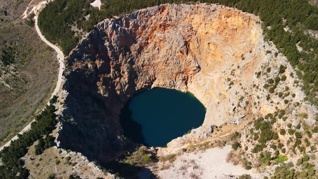 An aerial shot of Red Lake or Crveno jezero which is a collapsed sinkhole containing a karst lake close to Imotski, Croatia. It is 530 meters deep, thus it is the largest limestone crater in Europe.