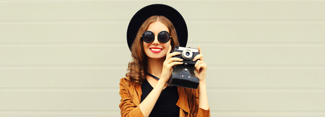 Portrait of happy smiling young woman photographer with film camera on gray background