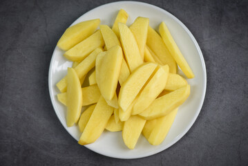 fresh raw potato wedges, chopped potatoes for cooked food on white plate