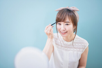 鏡の前で眉メイクをする若い女性
