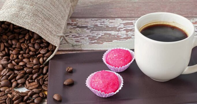 Brigadeiros bichos de pe next to a cup and coffee beans (side view).