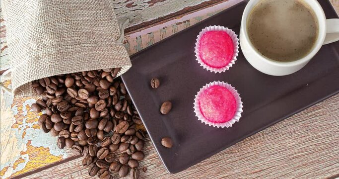 Coffee beans standing beside brigadeiros bicho de pe and a cup of coffee smoking (top view).