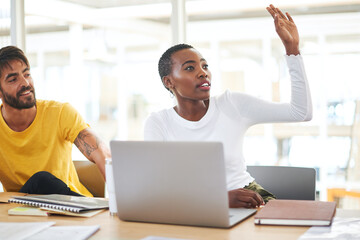 Ask more questions, gain more clarity. Shot of a young businesswoman raising her hand to ask a question during a meeting in a modern office.