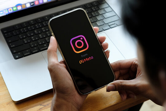 CHIANG MAI, THAILAND - FEB 26 2022: A man holds Apple iPhone 13 with Instagram application on the screen at cafe. Instagram from meta is a photo-sharing app for smartphones.