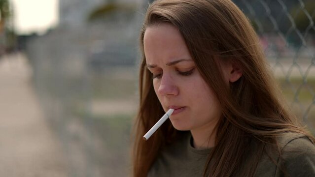Young dissatisfied woman lights a cigarette