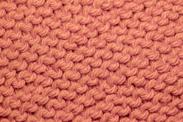 Macro abstract background of hand-knitted yarn fabric texture with a garter stitch pattern, in the color of salmon orange