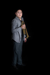Naklejka premium Young teenager energetically playing trumpet on black background