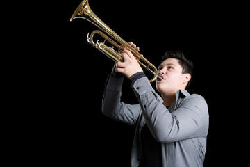 Young teenager energetically playing trumpet on black background