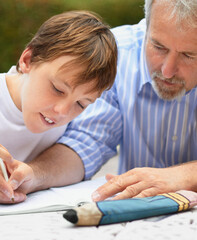 Helping him with his homework. Shot of a father helping his son with his homework.