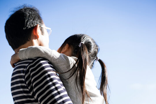 孫を抱く男性の後ろ姿と青空